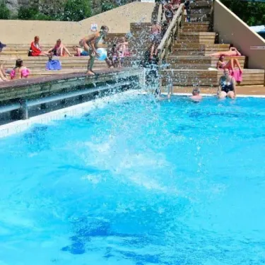 Camping Le Colporteur : enfants sautant dans la piscine en plein été