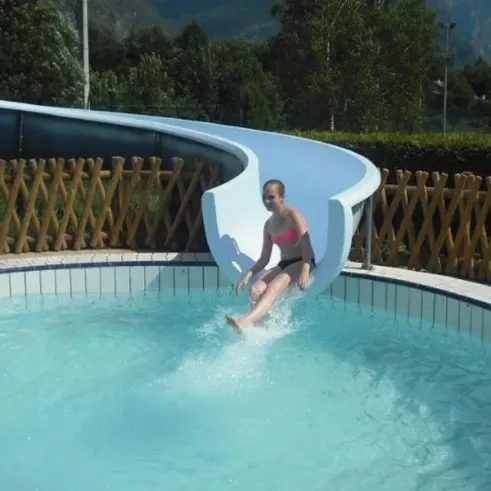 Camping Le Colporteur : enfant glissant sur toboggan aquatique dans une piscine entourée d'une clôture en bois.