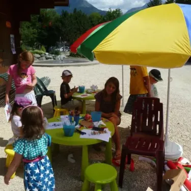 Camping Le Colporteur : enfants créant des dessins sous un parasol coloré