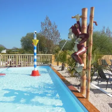 Statue de singe sur poteau bambou près de la piscine au Camping La Baie Dorée
