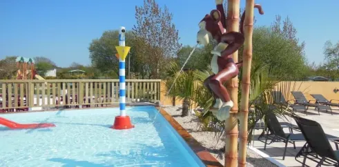 Statue de singe sur poteau bambou près de la piscine au Camping La Baie Dorée