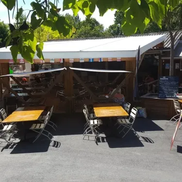 Tables et chaises en plein air sous un auvent au Camping Des Familles.