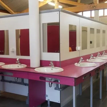 Salle de bains extérieure avec lavabos et miroirs au Camping du Port Mulon.