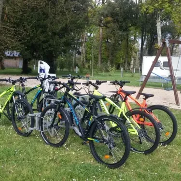 Vélos alignés sur l'herbe près d'une cabane et d'un parc de camping au Camping du Port Mulon
