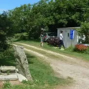 Camping Pré de la Mer : entrée avec panneau bleu et visiteurs près d'une allée