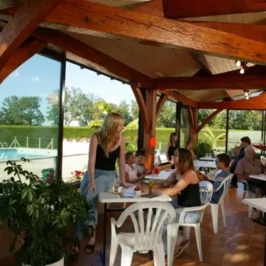 Camping La Nouvelle Croze : salle à manger en bois avec piscine visible à travers les vitres.