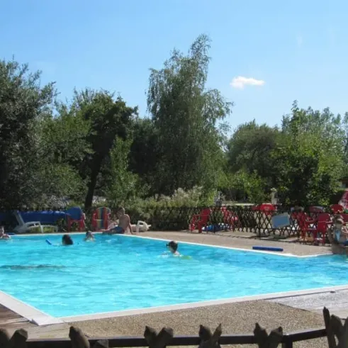 Piscine extérieure avec des personnes qui nagent et des chaises longues autour au Camping Ferme de Prunay