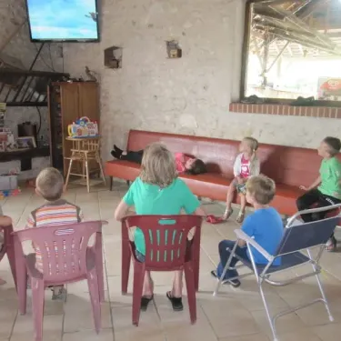 Enfants assis sur des chaises en plastique dans une salle de camping Camping Ferme de Prunay