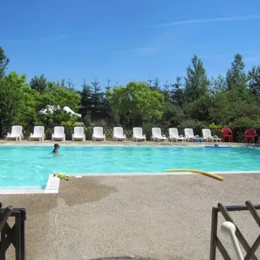 Piscine avec chaises longues et enfant nageant au Camping Ferme de Prunay