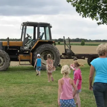 Enfants suivant un tracteur sur un champ, Camping Ferme de Prunay