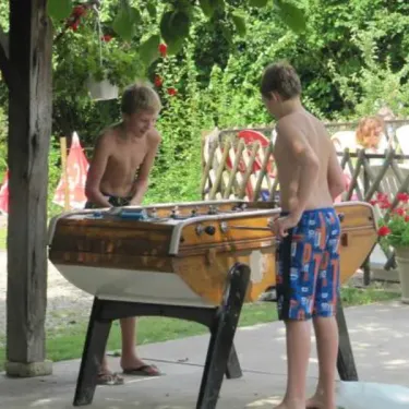 Deux garçons jouant au football à table sous un arbre dans le jardin du camping Camping Ferme de Prunay
