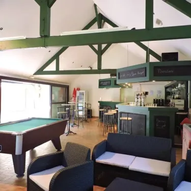 Camping La Plage de Garoustel : salle de jeux avec billard, bar et canapés en extérieur.