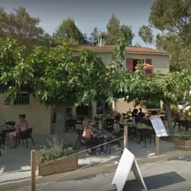 Terrasse extérieure du Camping U Pezzo avec tables, chaises et arbres