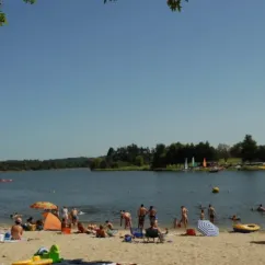 Plage animée avec parasols et baignade, Camping Des Lacs