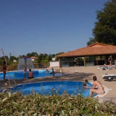 Piscine extérieure avec fontaine et chaises longues, Camping Des Lacs