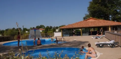 Piscine extérieure avec fontaine et chaises longues, Camping Des Lacs
