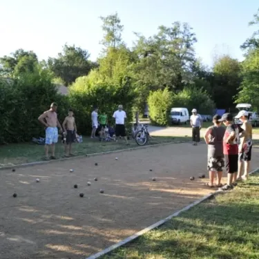 Des personnes jouant au boule sur un terrain de sable. Camping Des Lacs.