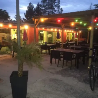 Camping Grand Sud - terrasse éclairée avec tables, chaises et vélo
