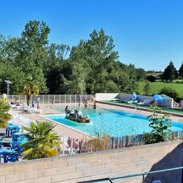 Piscine avec chaises bleues et palmiers au Camping Des Etangs