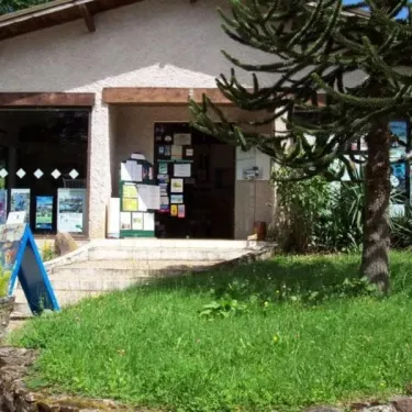 Entrée du Camping Le Manoir de Bezolle avec une arbre cactus et un panneau bleu.