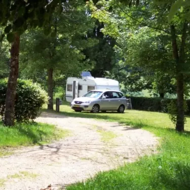 Caravane et voiture stationnées dans le parc du Camping Le Manoir de Bezolle