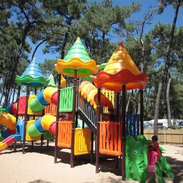 Piste de jeux colorée dans le camping La Plage de Riez, entourée d'arbres.