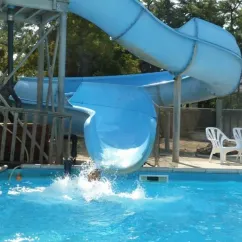 Glissière aquatique bleue à Camping Les Samaras, enfant tombant dans la piscine.