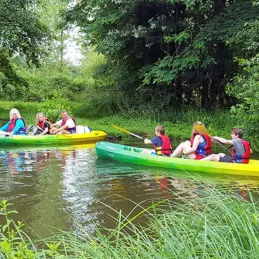 Groupes en kayak sur un cours d'eau verdoyant au Camping du Port Mulon