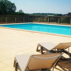 Piscine avec transats sur une terrasse en pierre à Camping La Nouvelle Croze
