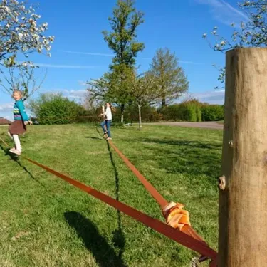 Enfants qui équilibrent sur un câble tendu entre deux poteaux en bois, au Camping Des Lacs.