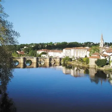 Camping Des Lacs près d'un lac avec des arbres et un pont en pierre