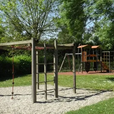 Parc infantile en bois avec toboggan et échelles dans un espace verdoyant
