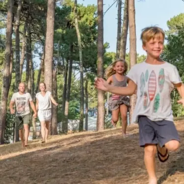 Famille qui court dans la forêt du Camping Slow Village.