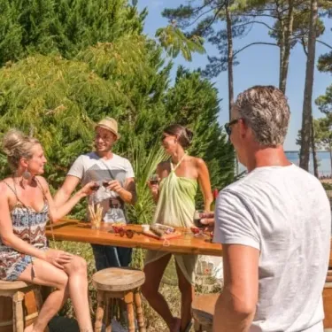 Groupes de personnes profitant d'un repas en extérieur autour d'une table en bois au Camping Slow Village