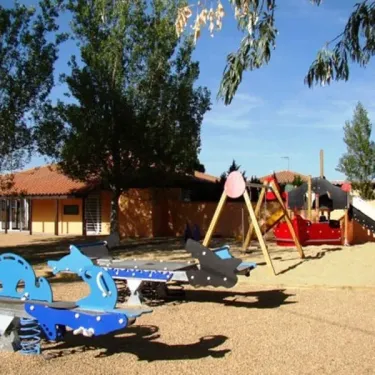 Parc infantile avec balançoire en forme de dauphin et toboggan rouge au Camping Port Camargue