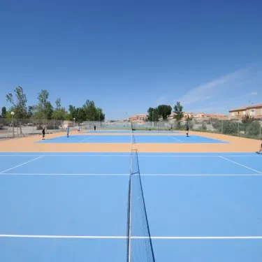 Terrain de tennis bleu avec des joueurs en train de jouer au Camping Port Camargue