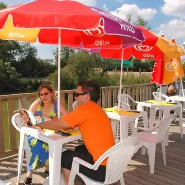 Un couple au Camping L'Etang de Besse, assis sous une ombrelle Mixo sur un ponton en bois.
