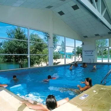 Piscine couverte avec des visiteurs nageant au Camping L'Etang de Besse