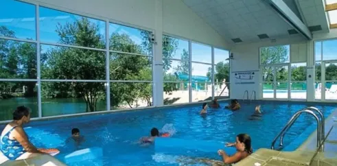Piscine couverte avec des visiteurs nageant au Camping L'Etang de Besse