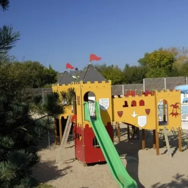 Camping Kerarno : parc d'attractions pour enfants avec château jaune et toboggan vert.
