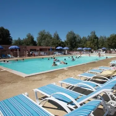 Lits de soleil bleus autour d'une piscine au Camping Les Demoiselles