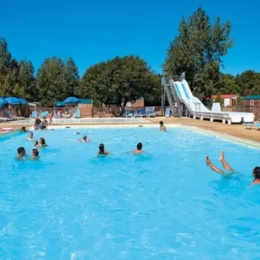 Piscine avec toboggan et enfants nageant au Camping Les Demoiselles