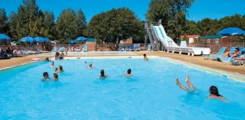 Piscine avec toboggan et enfants nageant au Camping Les Demoiselles