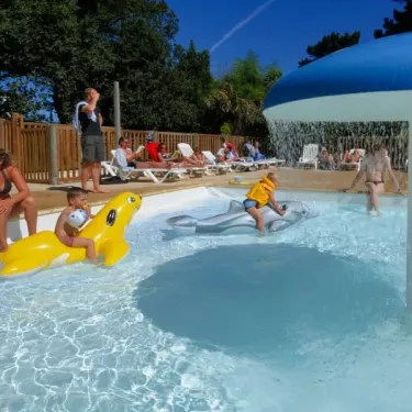 Camping Port de la Chaine : enfants dans une piscine avec flotteurs dauphin et structure d'eau.