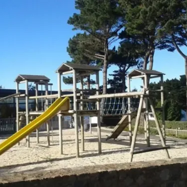 Camping Port de la Chaine : aire de jeu en bois avec toboggan jaune et structures pour enfants.