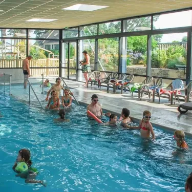 Piscine intérieure animée avec des enfants et adultes nageant au Camping Port de la Chaine