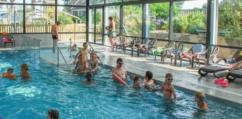 Piscine intérieure animée avec des enfants et adultes nageant au Camping Port de la Chaine