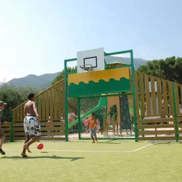 Enfants jouent au football près d'un panier basket en extérieur à Camping Les Albères.