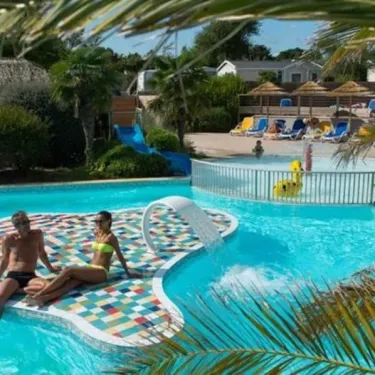 Un couple au bord d'une piscine à motifs colorés, dans le camping Les Iles.