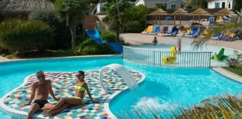 Un couple au bord d'une piscine à motifs colorés, dans le camping Les Iles.